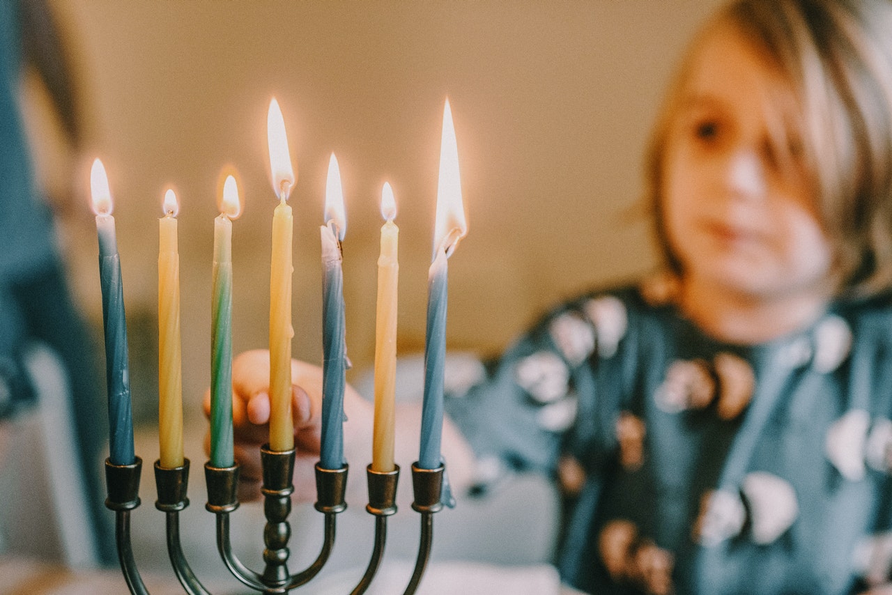 ילד מדליק נרות וממקם את השמש בחנוכיה